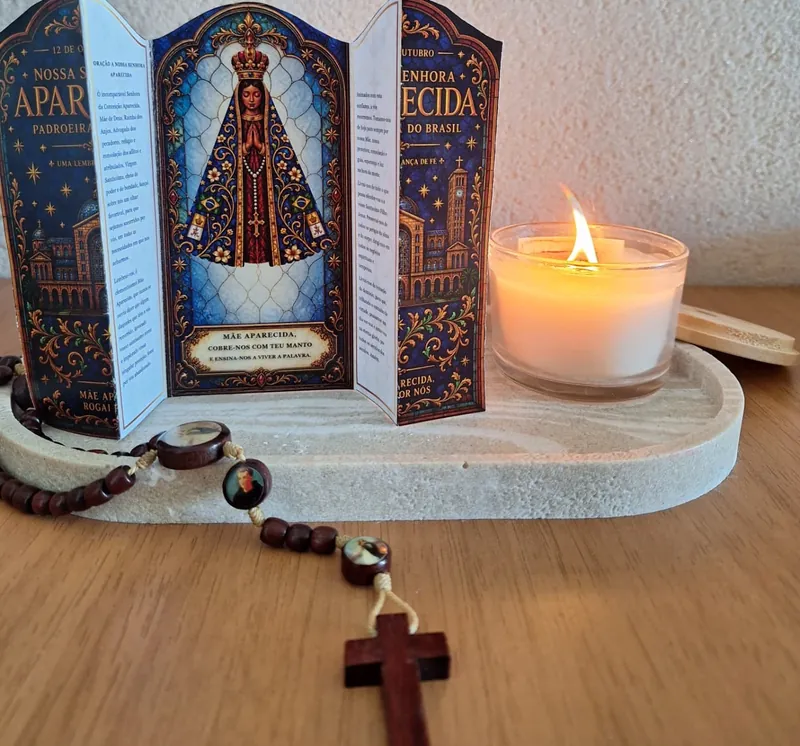 Oratório de Nossa Senhora Aparecida montado ao lado de vela acesa e terço